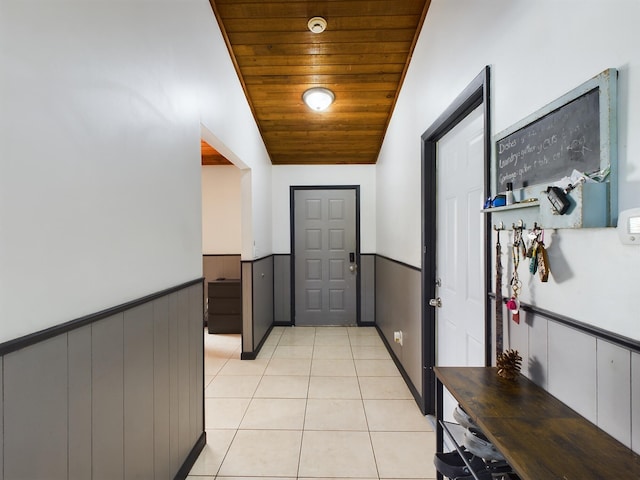 corridor with vaulted ceiling, light tile patterned floors, and wooden ceiling