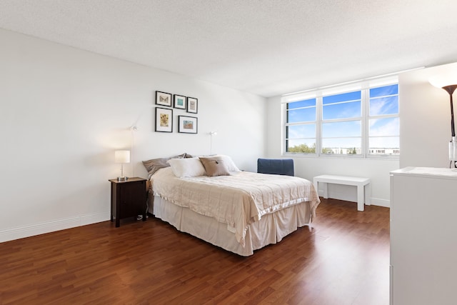 bedroom featuring baseboards, a textured ceiling, and dark wood-style flooring