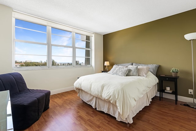 bedroom with dark wood-style floors, a textured ceiling, and baseboards