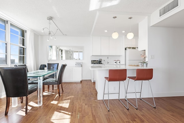 kitchen with visible vents, plenty of natural light, a kitchen breakfast bar, and freestanding refrigerator