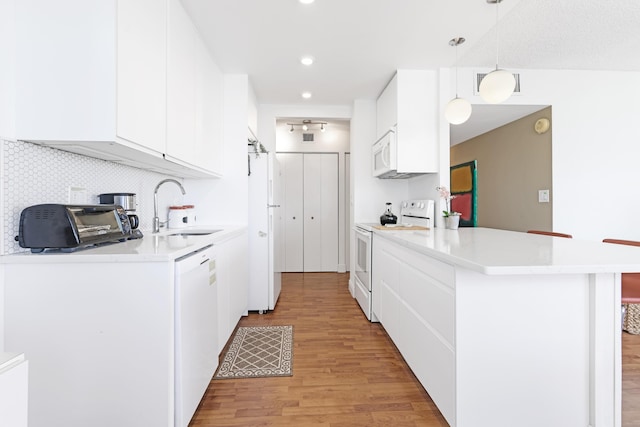 kitchen with white appliances, a sink, white cabinets, light wood-type flooring, and backsplash