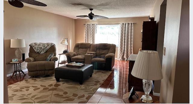 tiled living area with baseboards, ceiling fan, visible vents, and a textured ceiling