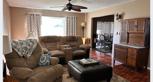 living area with a ceiling fan and a textured ceiling