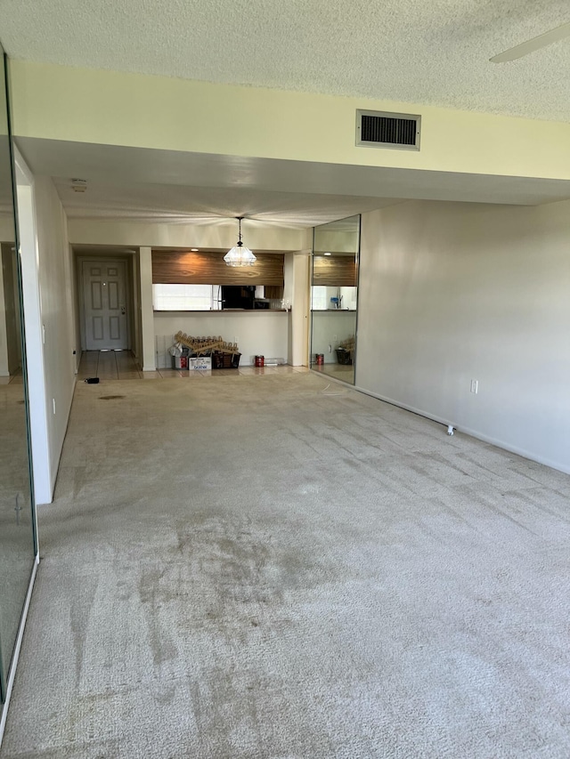 unfurnished living room with carpet floors and a textured ceiling