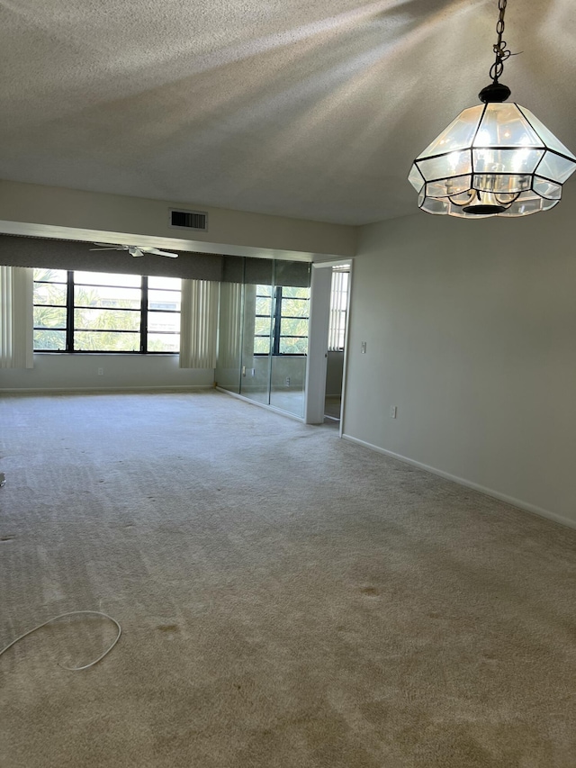 carpeted empty room with an inviting chandelier and a textured ceiling