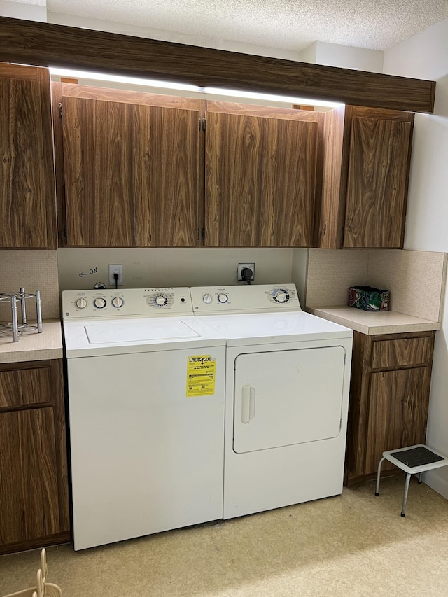 washroom with cabinets, washer and clothes dryer, and a textured ceiling