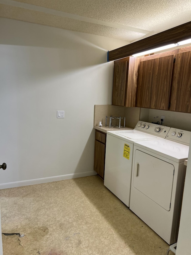 laundry room with cabinets, washer and clothes dryer, light colored carpet, and a textured ceiling