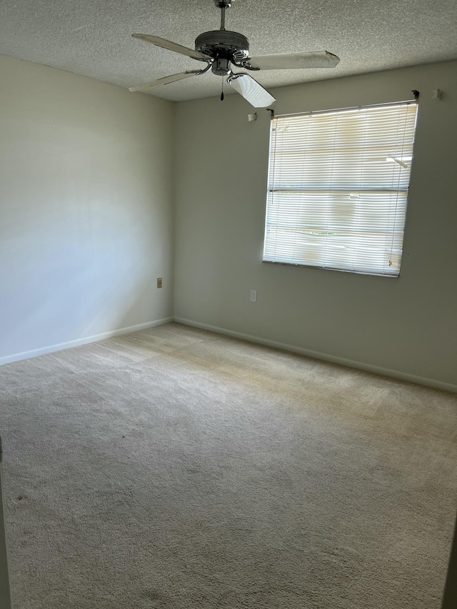 spare room featuring light carpet, ceiling fan, plenty of natural light, and a textured ceiling