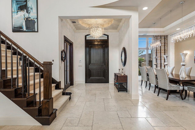 foyer entrance featuring a notable chandelier, a tray ceiling, and ornamental molding