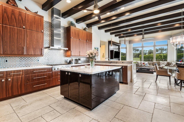 kitchen featuring pendant lighting, tasteful backsplash, a kitchen breakfast bar, a center island with sink, and wall chimney exhaust hood