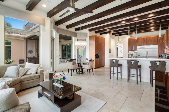 living room featuring beam ceiling and ceiling fan with notable chandelier