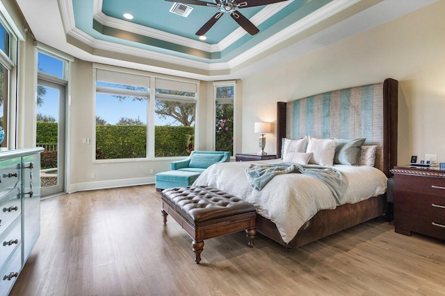 bedroom featuring crown molding, light hardwood / wood-style flooring, ceiling fan, access to exterior, and a tray ceiling