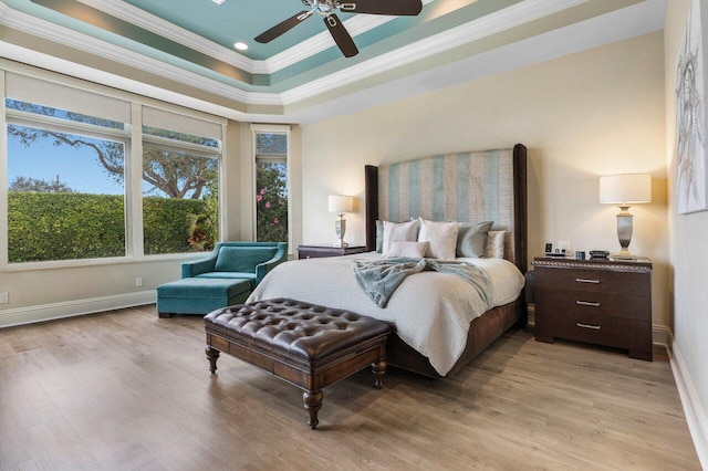 bedroom featuring crown molding, a tray ceiling, ceiling fan, and light hardwood / wood-style flooring