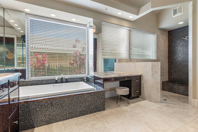 bathroom with tile patterned floors, vanity, tiled bath, and tile walls