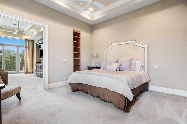 carpeted bedroom featuring ceiling fan, ornamental molding, a tray ceiling, and a walk in closet