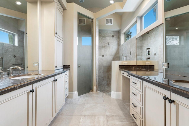 bathroom with a tile shower and vanity