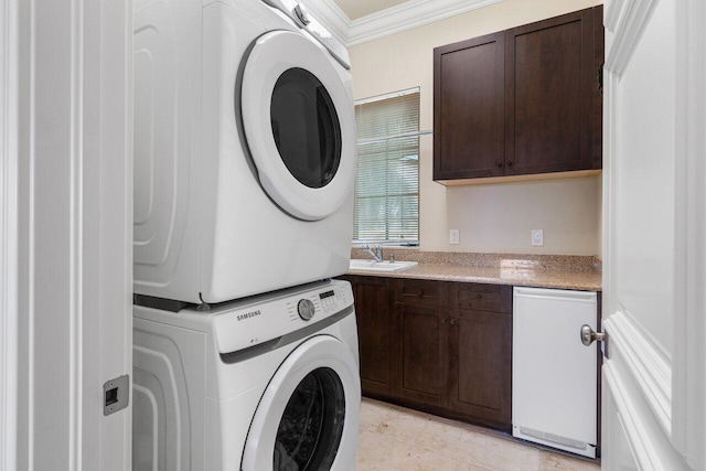 laundry area with stacked washer and dryer, sink, cabinets, light tile patterned floors, and ornamental molding