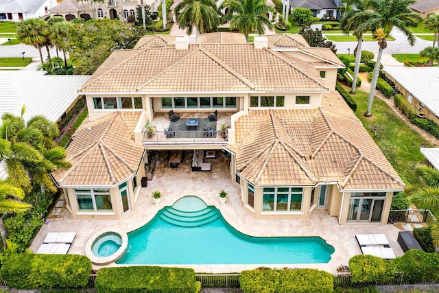 rear view of property with a patio and a pool with hot tub