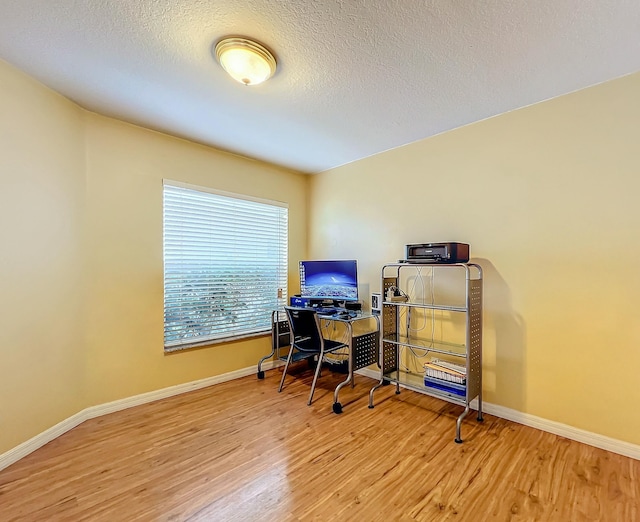 office with light hardwood / wood-style flooring and a textured ceiling