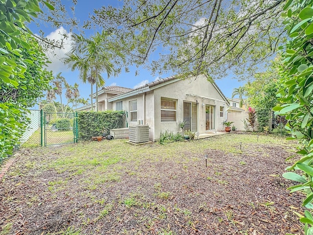 back of property featuring central AC and a lawn