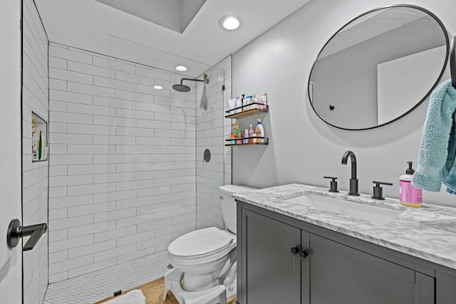 bathroom with vanity, tiled shower, and toilet