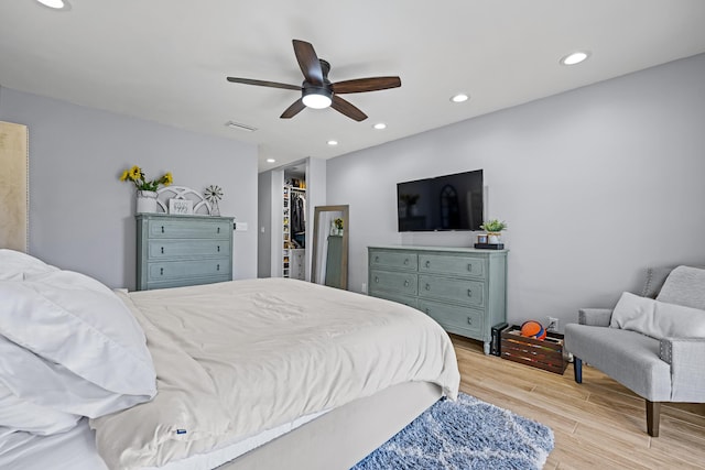 bedroom with a walk in closet, light hardwood / wood-style floors, and ceiling fan