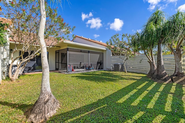 back of property featuring central AC unit, a yard, and a sunroom