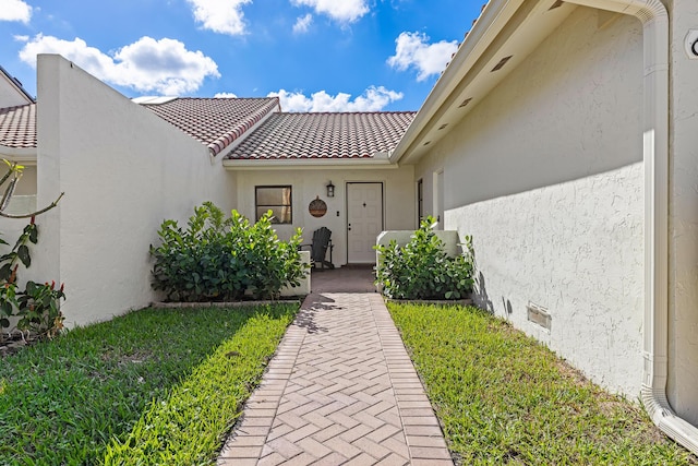 view of exterior entry with a yard