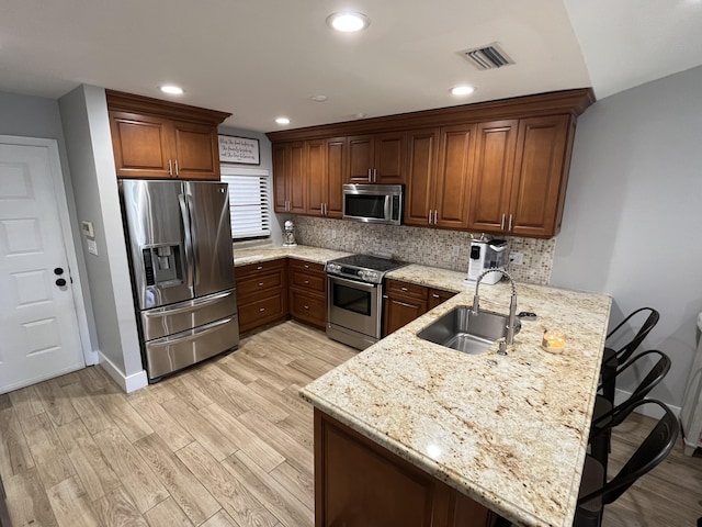 kitchen featuring appliances with stainless steel finishes, kitchen peninsula, sink, and a breakfast bar area