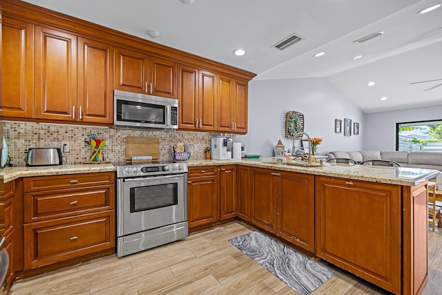 kitchen featuring lofted ceiling, sink, tasteful backsplash, kitchen peninsula, and stainless steel appliances