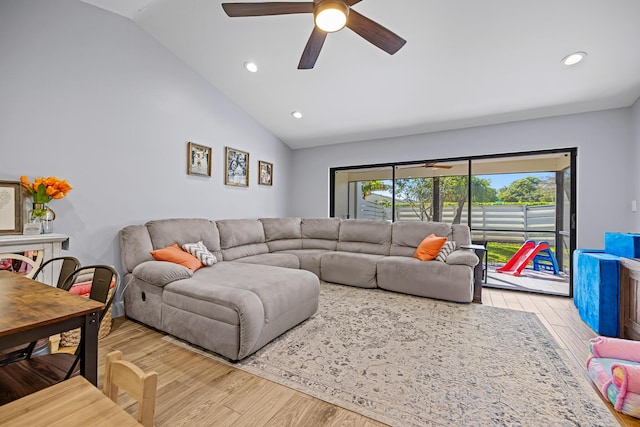 living room with lofted ceiling, ceiling fan, and light wood-type flooring