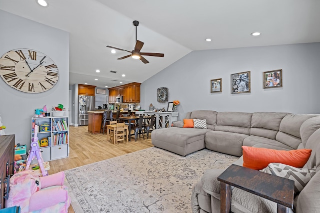 living room featuring ceiling fan, lofted ceiling, and light hardwood / wood-style floors