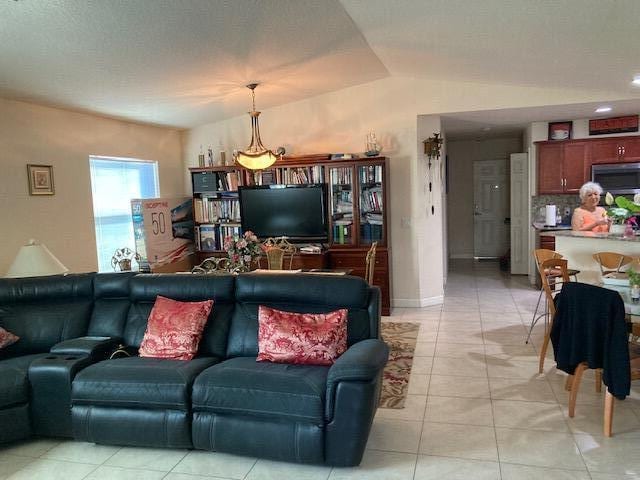 living room with light tile patterned floors and vaulted ceiling