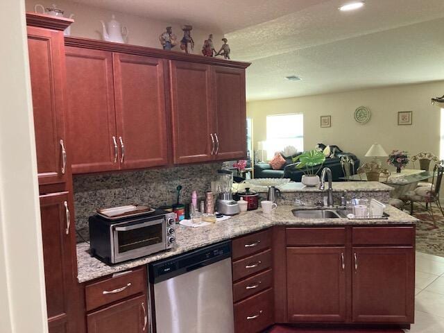 kitchen with tasteful backsplash, light tile patterned floors, stainless steel dishwasher, kitchen peninsula, and light stone countertops