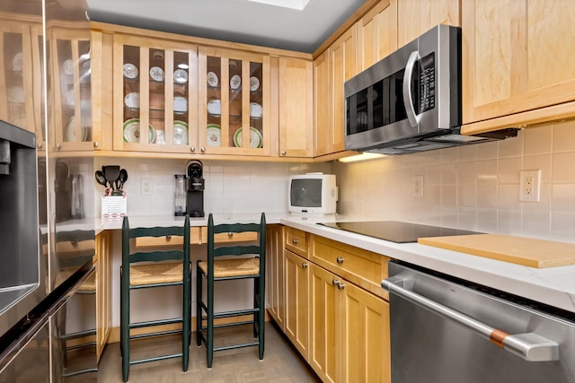 kitchen with backsplash, light brown cabinets, and appliances with stainless steel finishes