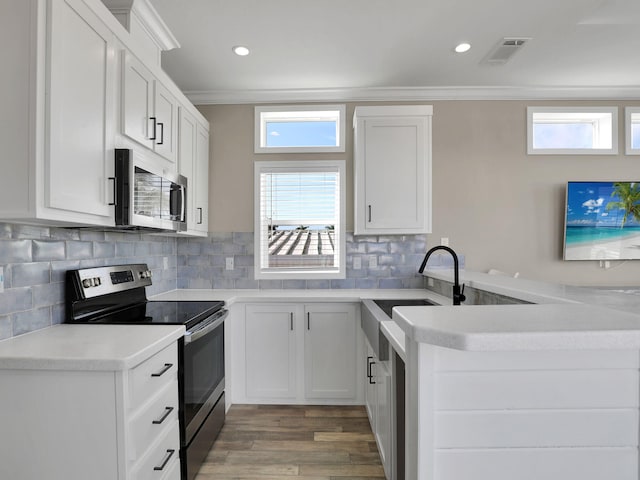 kitchen with appliances with stainless steel finishes, sink, white cabinets, and kitchen peninsula