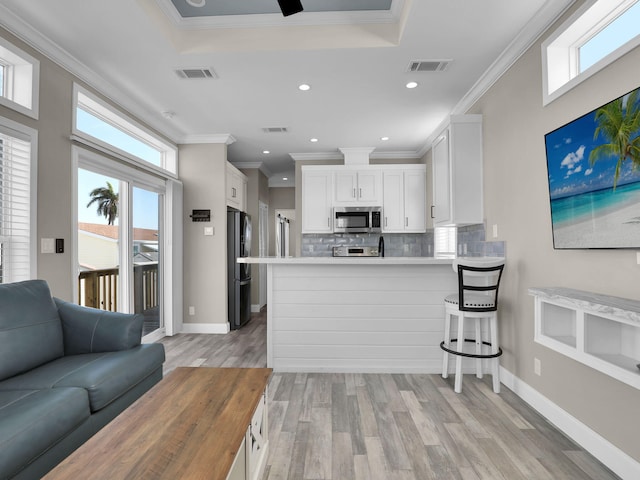 kitchen with a breakfast bar, white cabinetry, black refrigerator, kitchen peninsula, and a wealth of natural light