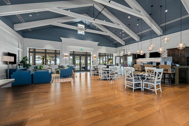 dining space featuring french doors, beam ceiling, hardwood / wood-style floors, and a high ceiling