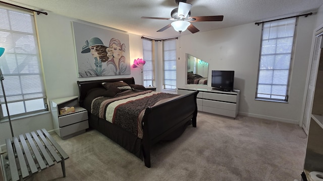 bedroom featuring ceiling fan, light colored carpet, and a textured ceiling