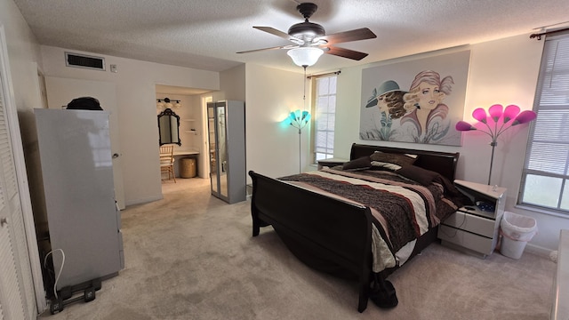 bedroom featuring ceiling fan, light colored carpet, refrigerator, and a textured ceiling