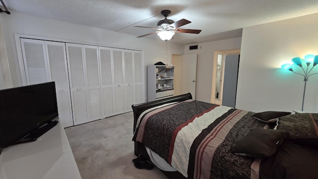 bedroom featuring light carpet, ceiling fan, a closet, and a textured ceiling