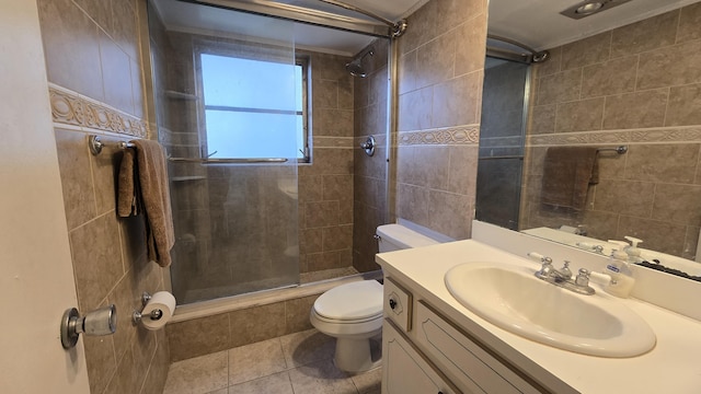 bathroom featuring tile patterned floors, vanity, toilet, and a tile shower