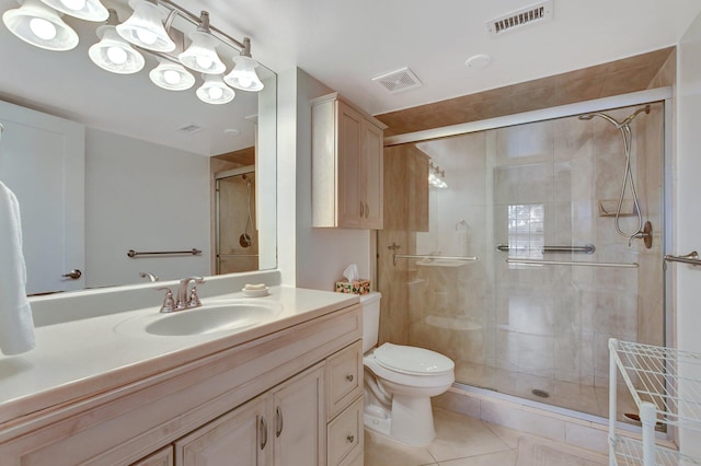 bathroom featuring a shower with door, vanity, tile patterned flooring, and toilet