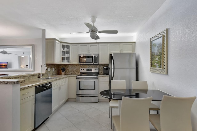 kitchen featuring appliances with stainless steel finishes, kitchen peninsula, sink, ceiling fan, and light stone counters