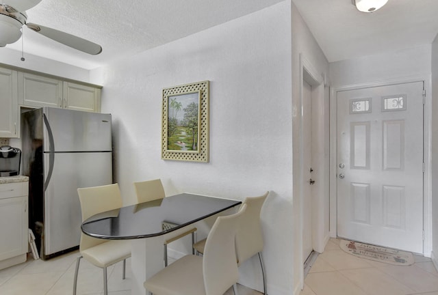 tiled dining room with ceiling fan and a textured ceiling