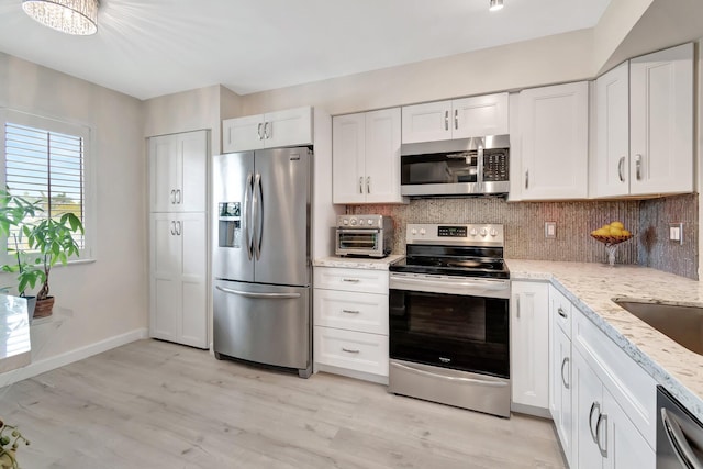 kitchen featuring white cabinetry, light stone counters, tasteful backsplash, and appliances with stainless steel finishes