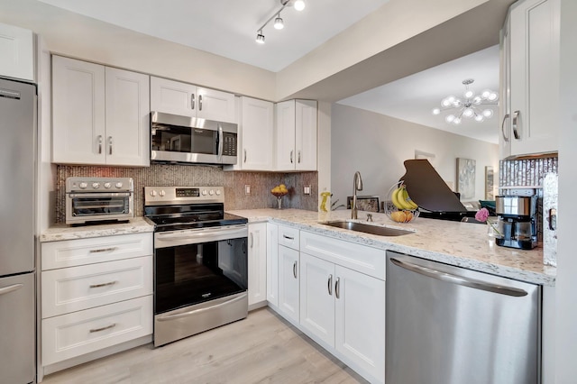 kitchen with white cabinetry, sink, decorative backsplash, and stainless steel appliances