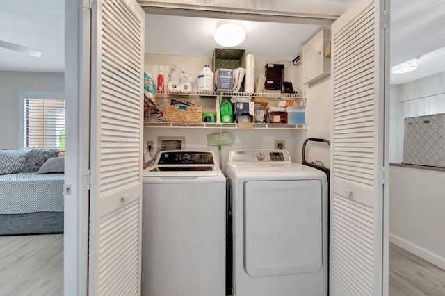 laundry room featuring washing machine and clothes dryer and light hardwood / wood-style floors