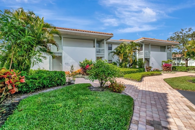 view of front of home with a balcony and a front lawn