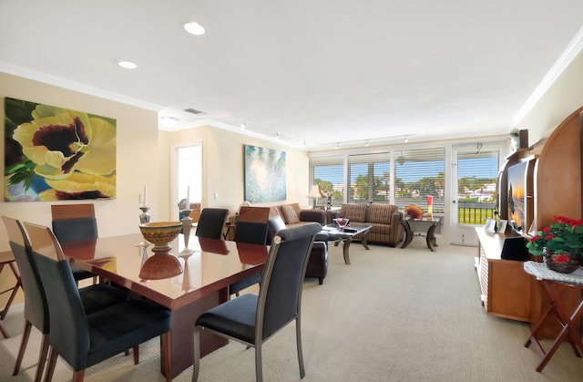 dining area featuring crown molding, track lighting, and light colored carpet